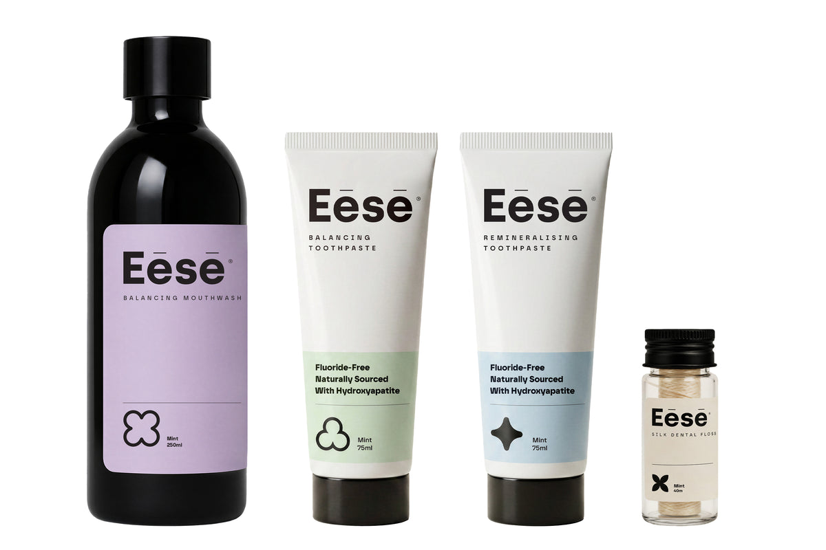 Eēsē oral care set featuring sodium lauryl sulfate free toothpaste tubes, a sleek black mouthwash bottle, and natural dental flosson a plain white background.