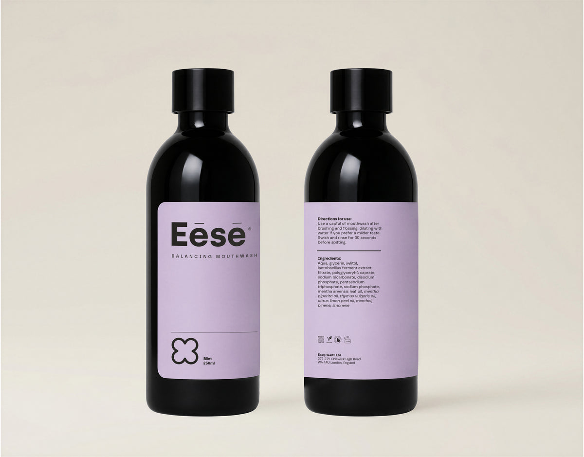 Two black bottles of Eēsē alcohol-free mouthwash in a sleek black bottle with a lavender label, photographed on a light beige background.